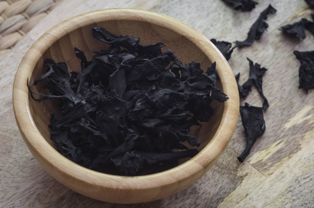 Dried black trumpet mushrooms in a wooden bowl.