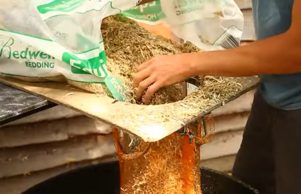 Putting chopped straw into a net bag for cold water lime bath pasteuriztion.