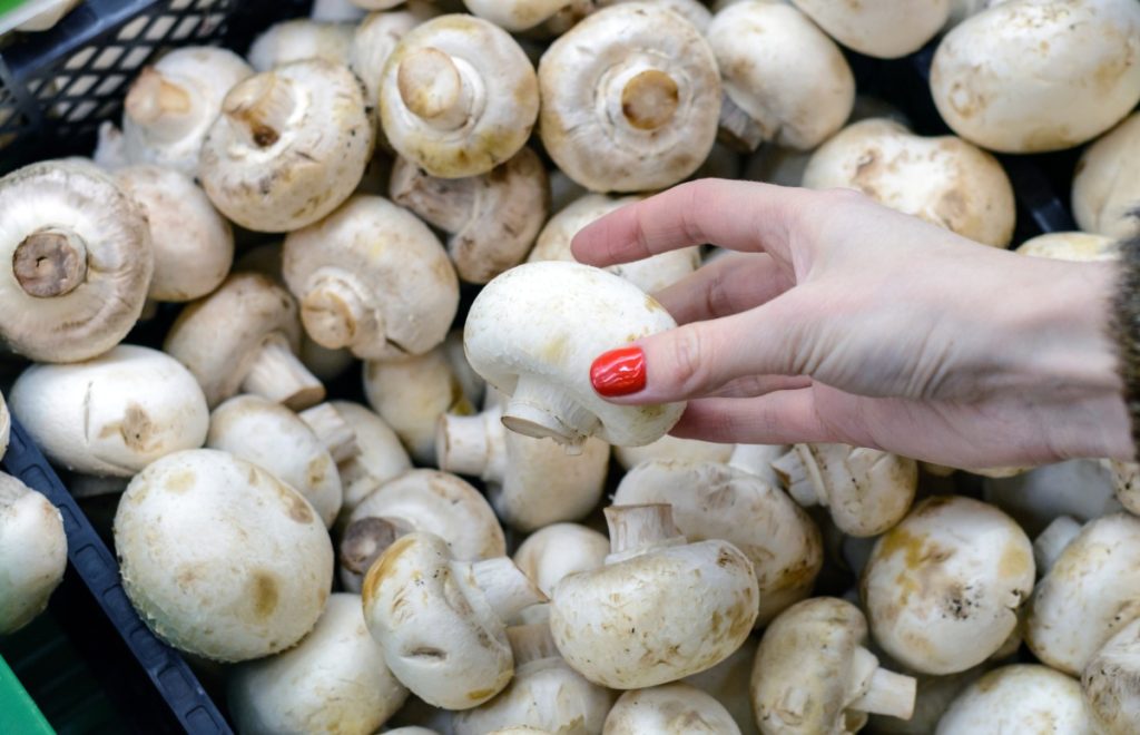 A woman selecting fresh button mushrooms