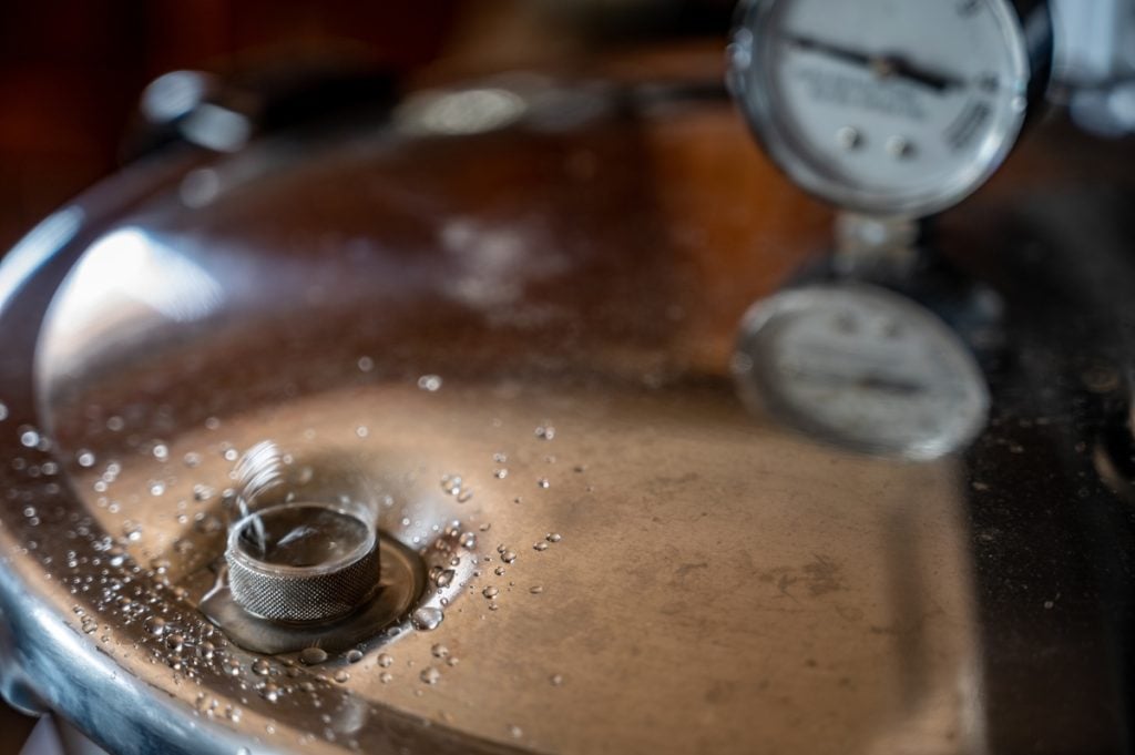 Steam and water droplets spluttering out of a pressure cooker vent