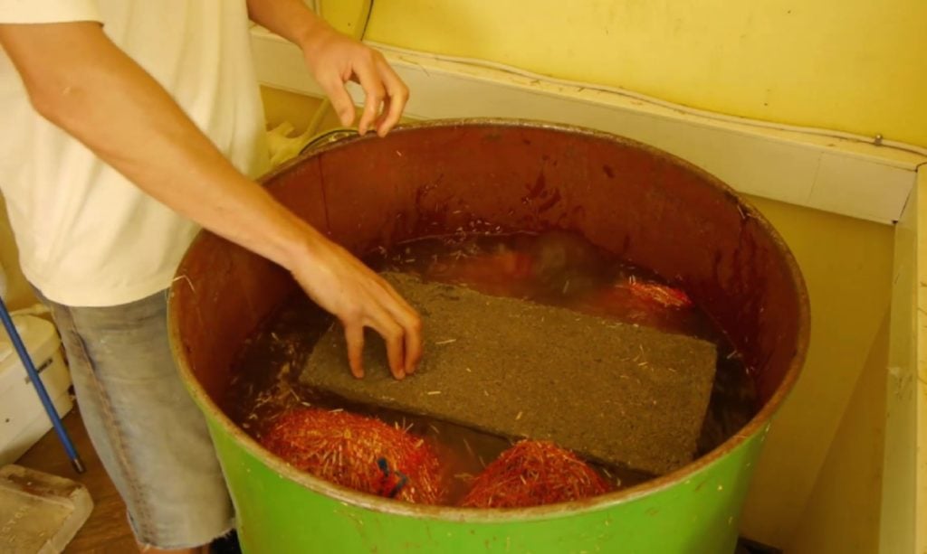 Putting a weight to keep straw submerged in a cold water pasteurization bath.