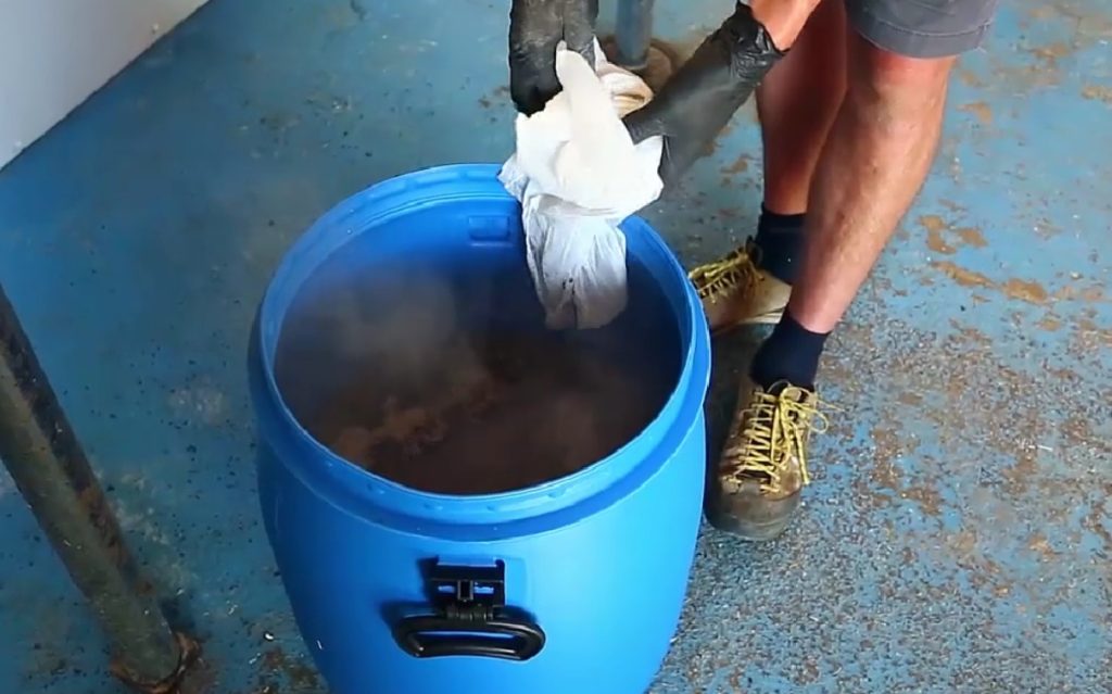 Adding wood ash to water for mushroom substrate pasteurization.