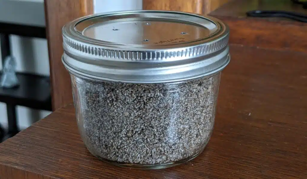 A wide mouth mason jar with nail holes in the lid